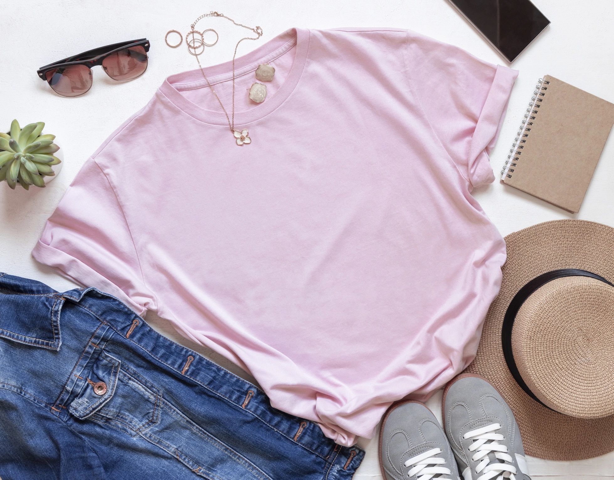 T-shirt flat lay with accessories on white wooden board