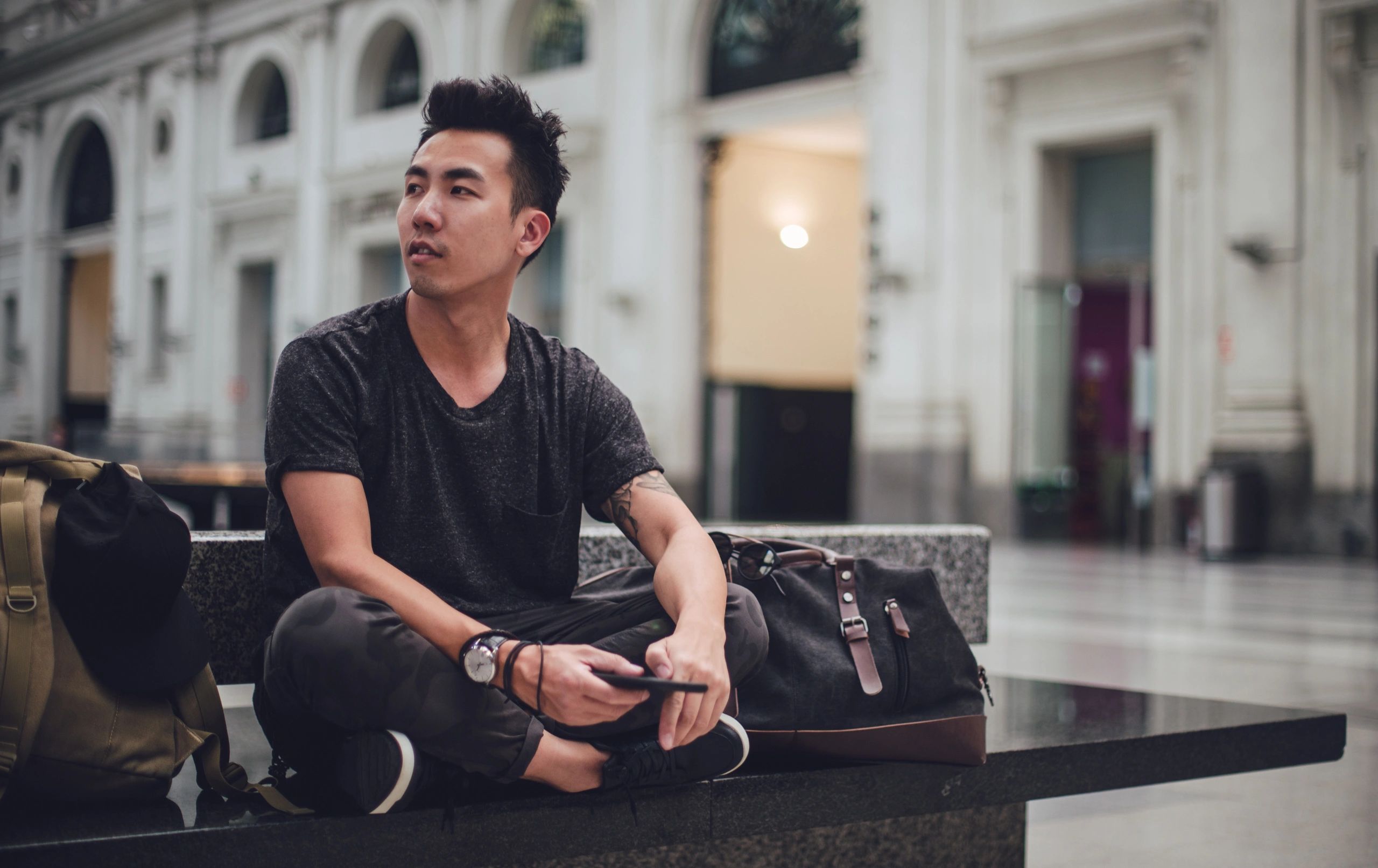 Young adult sitting on a subway bench using a phone